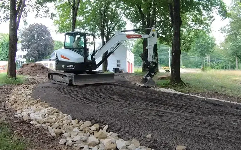 bobcat-mini-excavator-installing-6-8-inch-rip-rap-stone-to-support-edges-of-new-gravel-driveway-from-erosion
