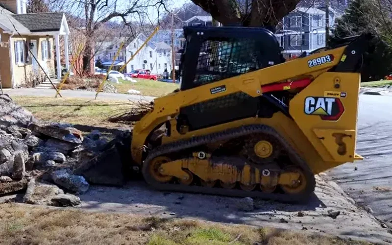 cat-289D3-track-skid-steer-ripping-up-cracked-asphalt-driveway-pavement