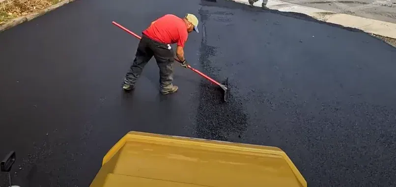 paving-crew-raking-out-hot-mix-to-blend-in-seam-new-paved-driveway